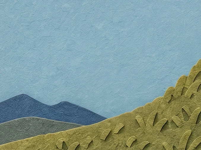 Distant blue hills, a round green bush and a grassy slope under a pale blue sky